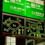Night scene of a large green road sign with white text directing to Hakozaki, Route 6, 601 entrance, Circle 1, and Joban Expressway.